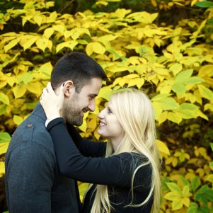 couple embraces one another for an intimate engagement portrait in front of yellow fall foliage