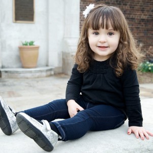 portrait of little girl sitting on a stone fountain in mellon park