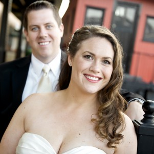 bride and groom smiling at camera with a red caboose train car in background